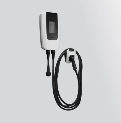 Electric vehicle charging station with coiled cable on a gray wall.