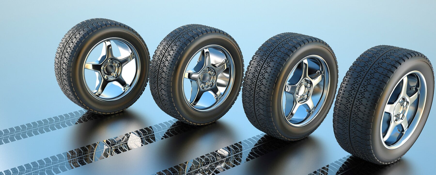 Four car tires with chrome rims on a reflective surface leaving tread marks.