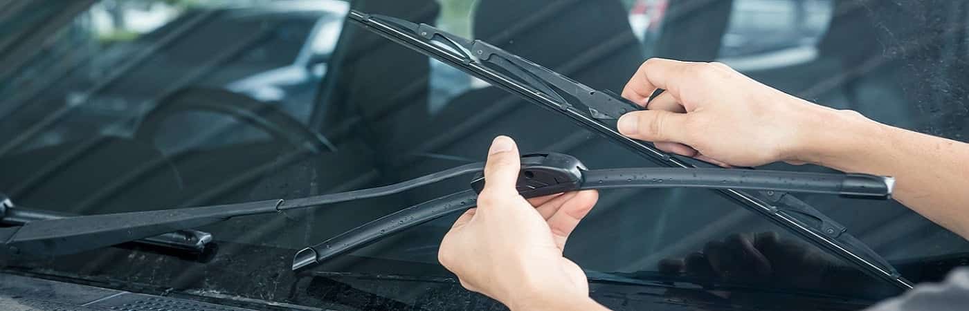 Person replacing a windshield wiper blade on a car, highlighting vehicle maintenance.