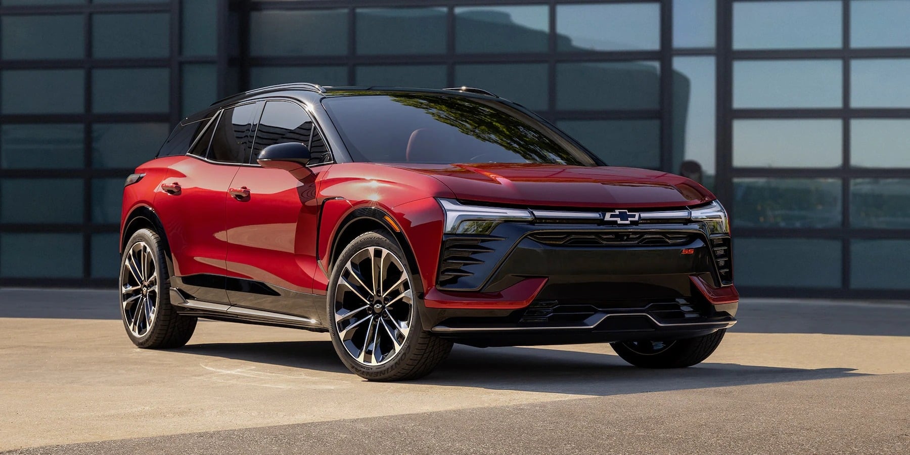 Red Chevrolet electric SUV parked in front of a building, showcasing sleek design and alloy wheels.