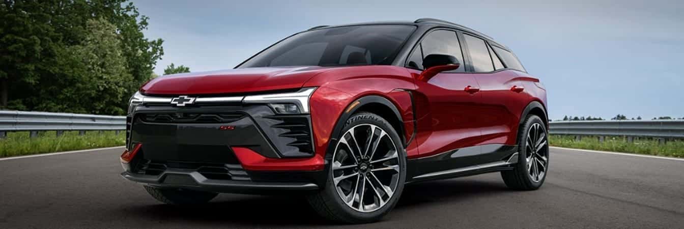 Red Chevrolet SUV on a road, with sleek design and modern alloy wheels, surrounded by greenery.